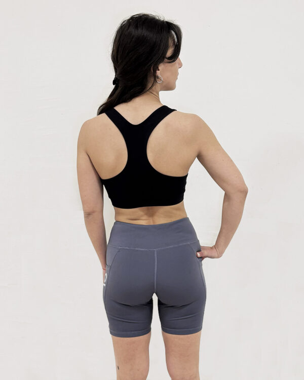 Mujer de espaldas utilizando una calza corta de color gris