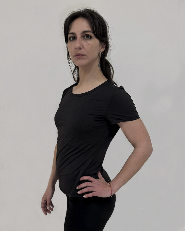 Mujer de perfil utilizando una polera manga corta de color negro con el logo de Virtual Bike