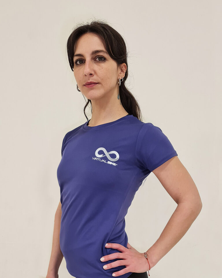 Mujer de perfil utilizando una polera manga corta de color morado con el logo de Virtual Bike
