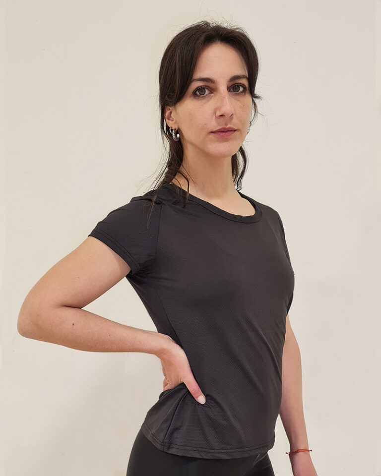 Mujer de perfil utilizando una polera manga corta de color negro con el logo de Virtual Bike