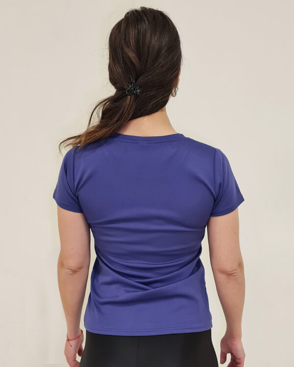 Mujer de espaldas utilizando una polera manga corta de color morado con el logo de Virtual Bike