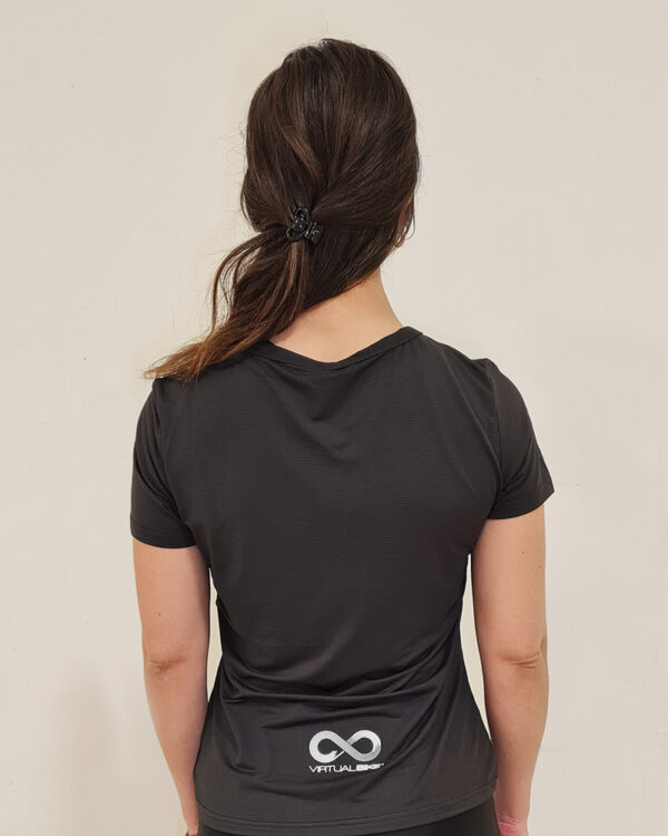 Mujer de espaldas utilizando una polera manga corta de color negro con el logo de Virtual Bike