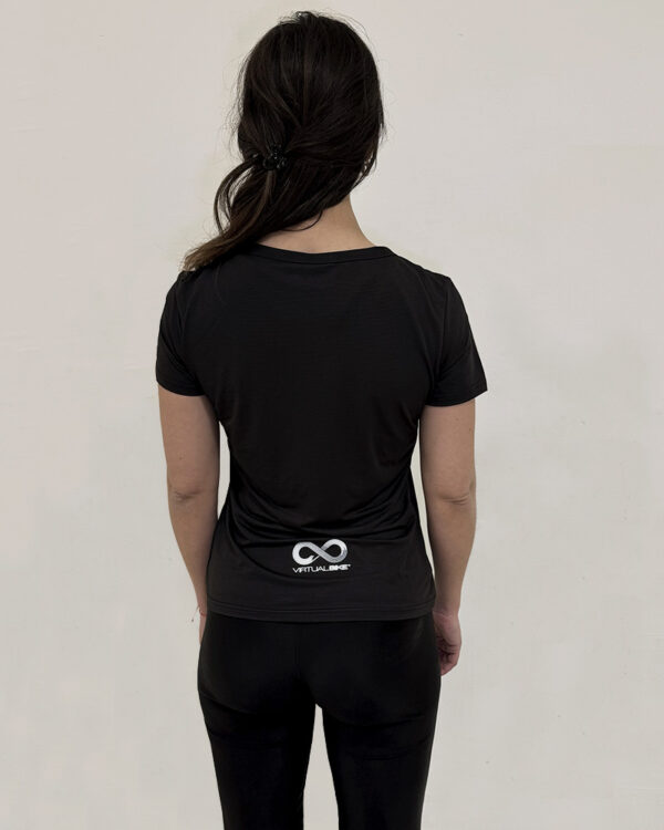 Mujer de espaldas utilizando una polera manga corta de color negro con el logo de Virtual Bike