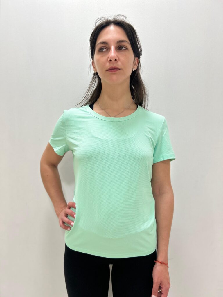 Mujer utilizando una polera verde pastel con logo de Virtual Bike en la espalda